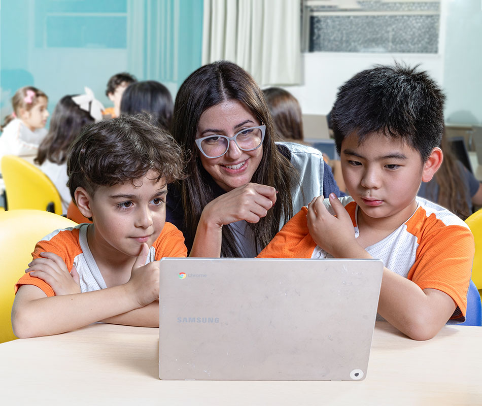 Professora mediando trabalho de alunos em letramento digital